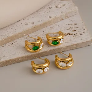 Détail des créoles en forme de C plaquées or 18 carats avec zircons verts et blancs