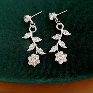 Detailed close-up of silver-tone leaf and flower earrings with rhinestones