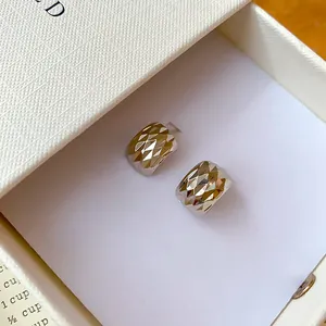 Vue détaillée de boucles d'oreilles carrées géométriques dans leur écrin de luxe.