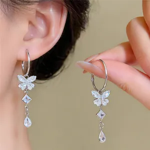 Close-up van elegante zilveren vlinderkwastoorbellen met sprankelende zirkoon.