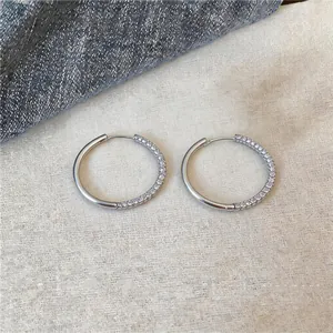 Close-up of minimalist silver circular hoop earrings with rhinestone micro-pave details