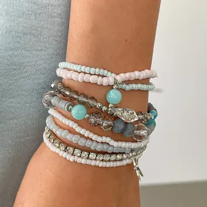 Detail of 8-piece stacked glass bead bracelets with rhinestones and star charms on arm