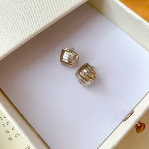 Gros plan de boucles d'oreilles géométriques carrées en argent avec une surface ondulée.