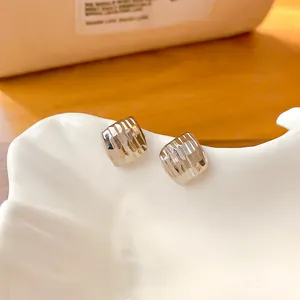 Vue macro de boucles d'oreilles géométriques dorées minimalistes avec une texture facettée