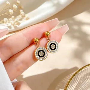 Detail view of circular titanium steel earrings with black enamel and sparkling crystals