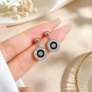 Close-up of minimalist titanium steel round earrings with crystals and black enamel.