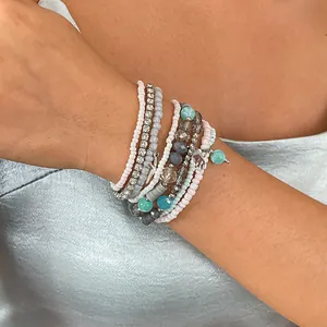 Close-up of layered 8-piece rhinestone and star beaded bracelets on model's wrist