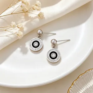 Close-up of minimalist titanium steel circle earrings with sparkling rhinestones and black enamel