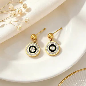Detail showing elegant 18k gold plated circular stud earrings with black enamel and crystals.