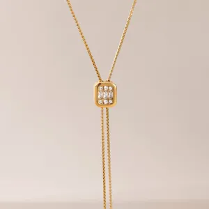 Détail d'un pendentif carré plaqué or avec des strass brillants sur chaîne