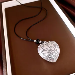 Vintage hartvormige hanger ketting met gedetailleerde bloemengravures en zwart koord