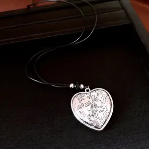 Harthanger ketting met zwart koord en bloemengravure op een zwart presentatiebord