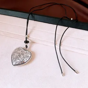 Halsketting met gegraveerde hart hanger aan minimalistisch zwart lederen koord, vintage
