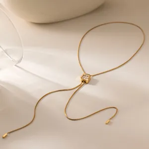 Détail du collier avec pendentif carré doré orné de strass brillants et réglable