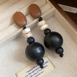 Detailansicht langer Ohrhänger mit Holz- und Acrylperlen in einem Schmucktablett