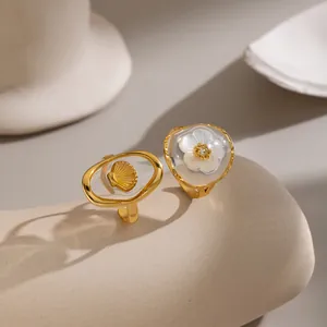 Detaillierte Ansicht von goldenen Edelstahlringen mit Muschel- und Blumenharzmotiven.