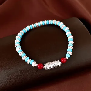 Detailed view of a handmade beaded bracelet with Bodhi seeds and engraved silver charm.