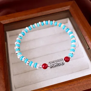 Detailed view of Bodhi beads and turquoise bracelet with an engraved silver charm