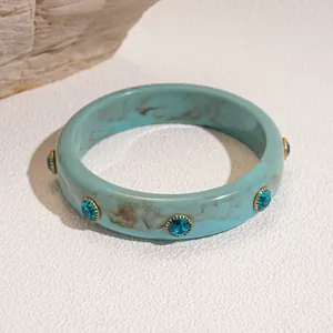 Elegant teal marbled resin bangle featuring sparkling blue rhinestones in gold settings