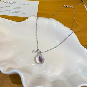 Détail du pendentif en résine glacée avec zircon violet sur une chaîne argentée