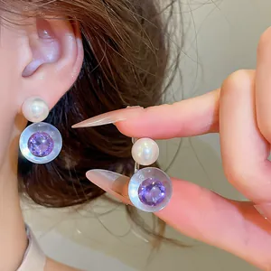 Détail de zircon violet facetté dans une boucle d'oreille en résine avec perle blanche