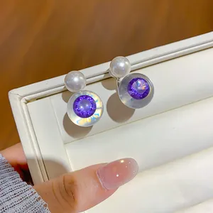 Gros plan détaillé des boucles d'oreilles en résine avec zircon violet et perle