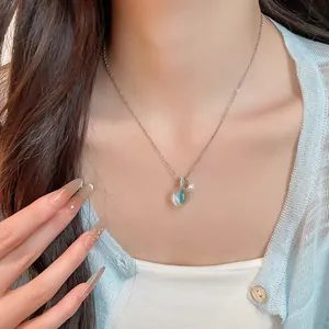 Vue détaillée d'un collier en résine glacée avec pendentif en zircon bleu-vert sur modèle