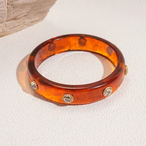 Elegant amber resin bangle with embedded sparkling crystal rivets for a luxury look.