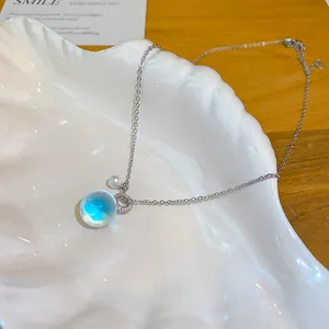 Détail du collier avec pendentif en résine translucide, zircon brillant et perle