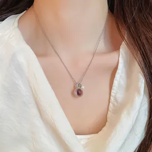 Détail élégant d'un collier chaîne ras du cou argenté avec pendentif en résine et zircon.
