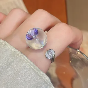 Gros plan exquis d'une bague en résine transparente avec zircon violet et argent au doigt