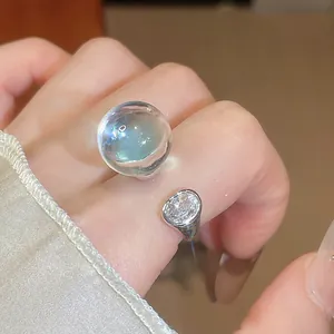 Gros plan détaillé d'une bague ajustable avec sphère en résine et pierre en zircon.