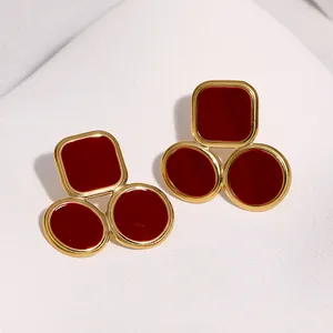 Macro view of geometric gold-plated stainless steel earrings with deep red enamel finish
