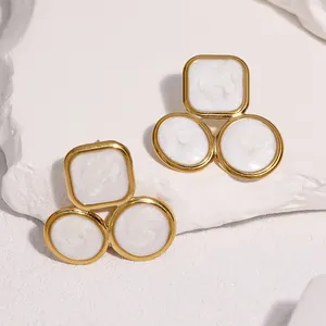 Detailed close-up view of French style geometric gold-plated earrings with white enamel
