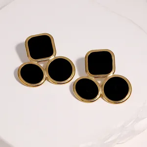 Detailed view of geometric gold-plated titanium steel earrings with black enamel inlays.