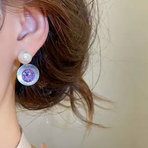 Gros plan de boucle d'oreille ronde en résine avec zircon violet et perle