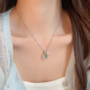 Gros plan d'un collier avec pendentif rond en résine porté par un mannequin sur la clavicule