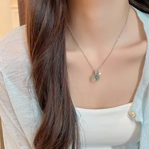 Détail d'un collier en chaîne argentée avec un pendentif en résine transparente.