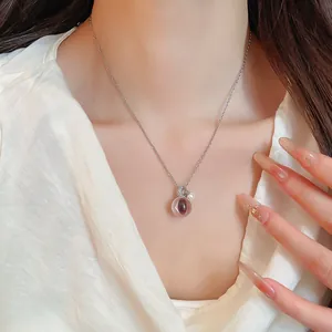 Gros plan d'un collier avec pendentif boule en résine transparente porté par un modèle.