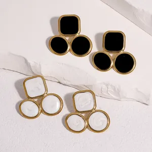 Detailed view of geometric gold-plated stainless steel earrings in black and white oil