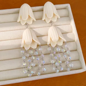Close-up of elegant cream acrylic flower tassel earrings with shimmering crystal beads