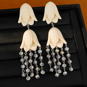 Close-up of elegant cream acrylic flower tassel earrings with crystal beads