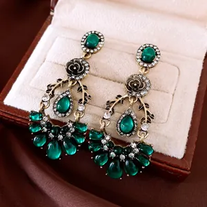 Close-up of vintage emerald green teardrop earrings with intricate floral and diamond accents