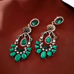 Close-up of vintage chandelier earrings with emerald green stones and rhinestones