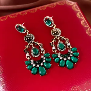 Macro detail of vintage emerald green teardrop earrings with rhinestone accents