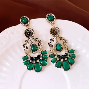 Detail view of vintage green teardrop earrings with sparkling rhinestones and gold finish