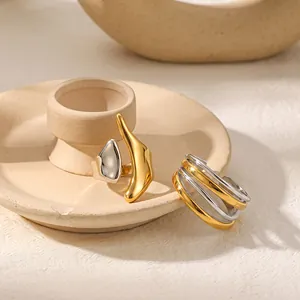 Detail van onregelmatige 18k goud vergulde roestvrijstalen ringen op een keramische schaal.