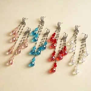 Boucles d'oreilles vintage avec glands en verre rose, bleu, rouge et clair sur fond beige.