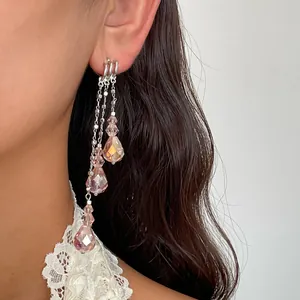 Gros plan d'élégantes boucles d'oreilles pendantes en cristal rose en forme de goutte