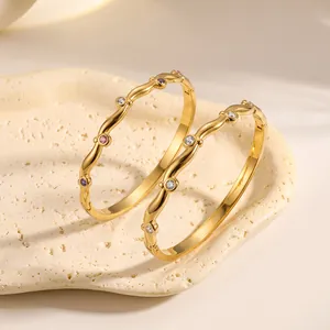 Dettaglio di bracciali rigidi in acciaio inossidabile placcato oro 18k con zirconi colorati.